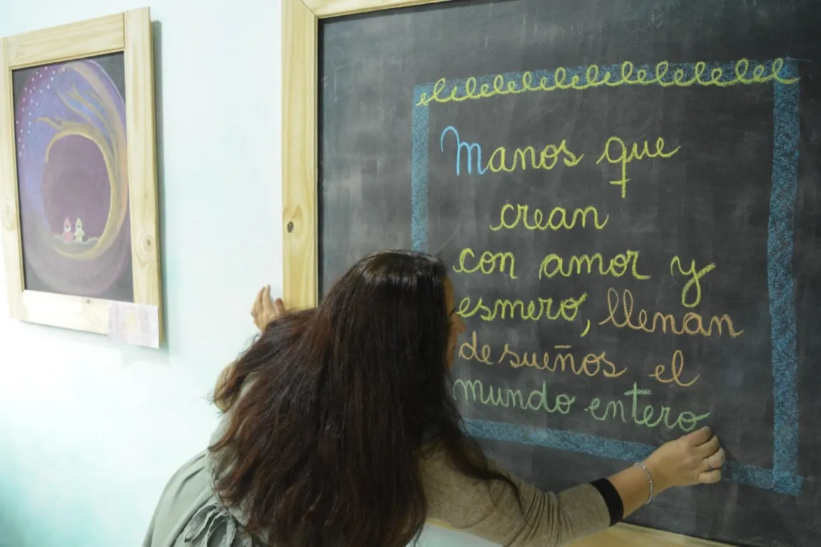 Aula Waldorf con bancos de madera y trabajos de los niños y niñas en la pared