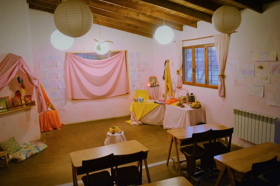 Aula Waldorf preparada con telas, dibujos de los niños y niñas, y lámparas suaves