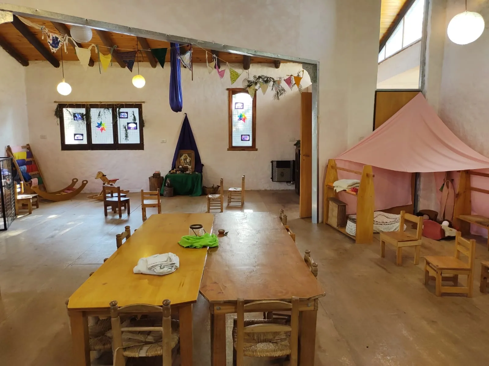 Niñas y niños del jardín siendo recibidos por una maestra en un entorno cálido y hogareño