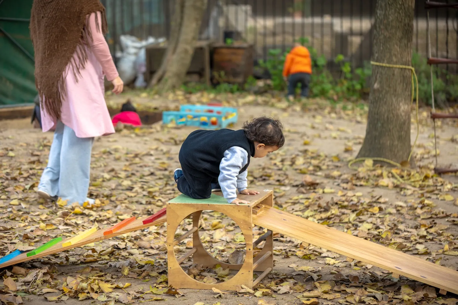 Niño pequeño trepando una estructura de madera al aire libre, explorando el movimiento autónomo