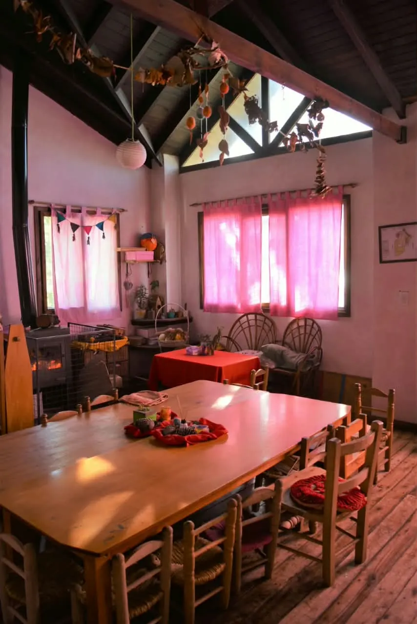 Sala del jardín de la Escuela de la Aurora, con mesas de madera y materiales naturales